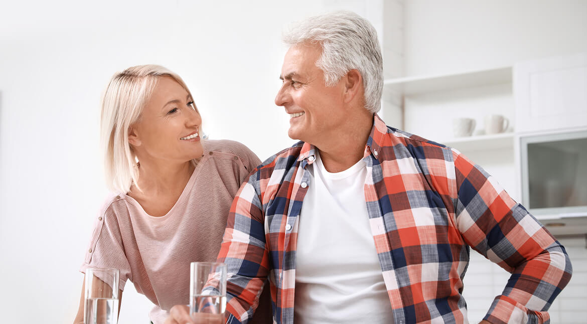 A man and woman smile at each other while seated at a table, creating a warm and friendly atmosphere.