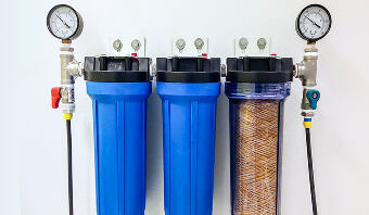 Three water filters mounted on a wall, showcasing their sleek design and functional placement for easy access.